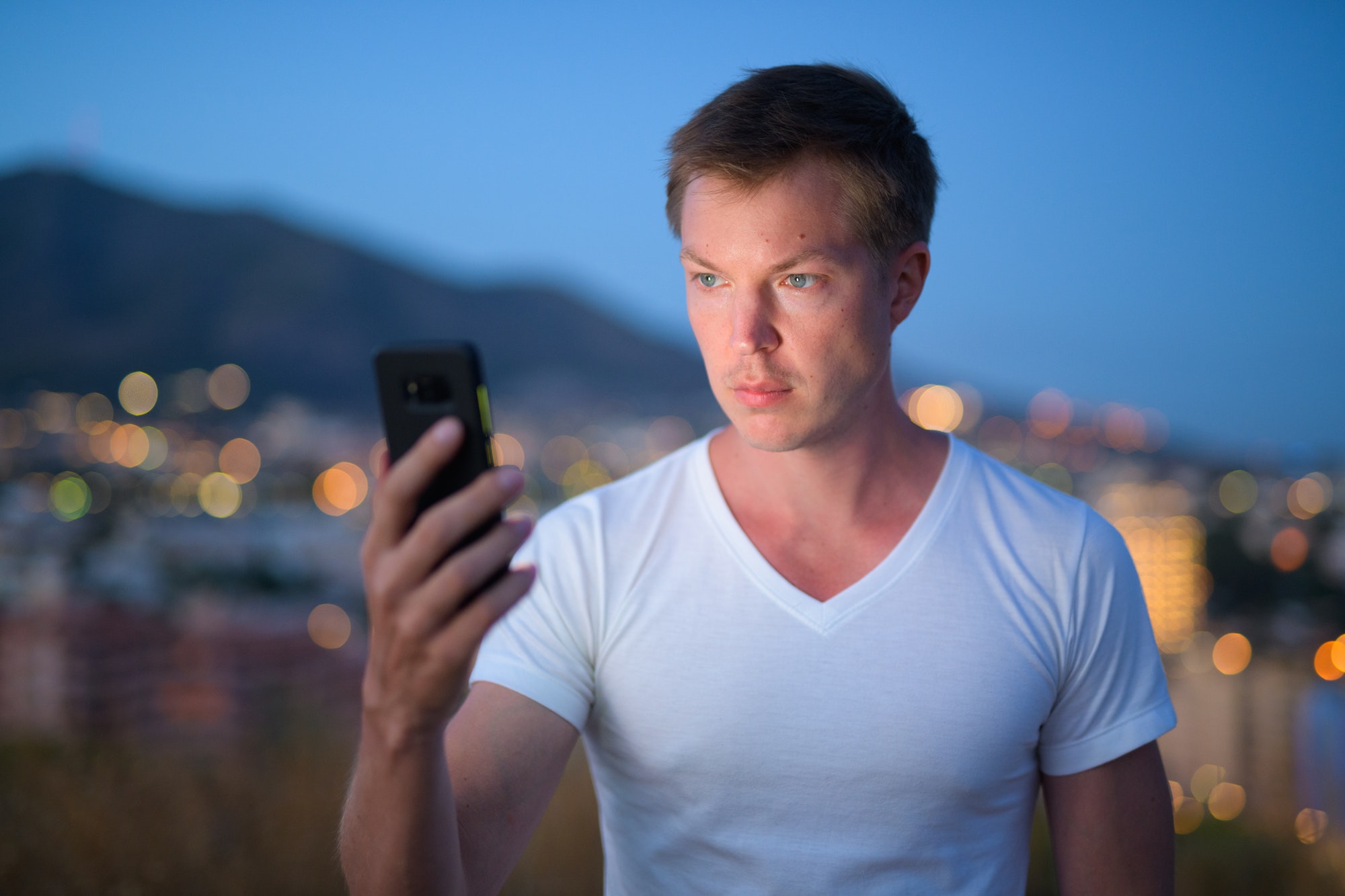An influencer using mobile phone outdoors at night.