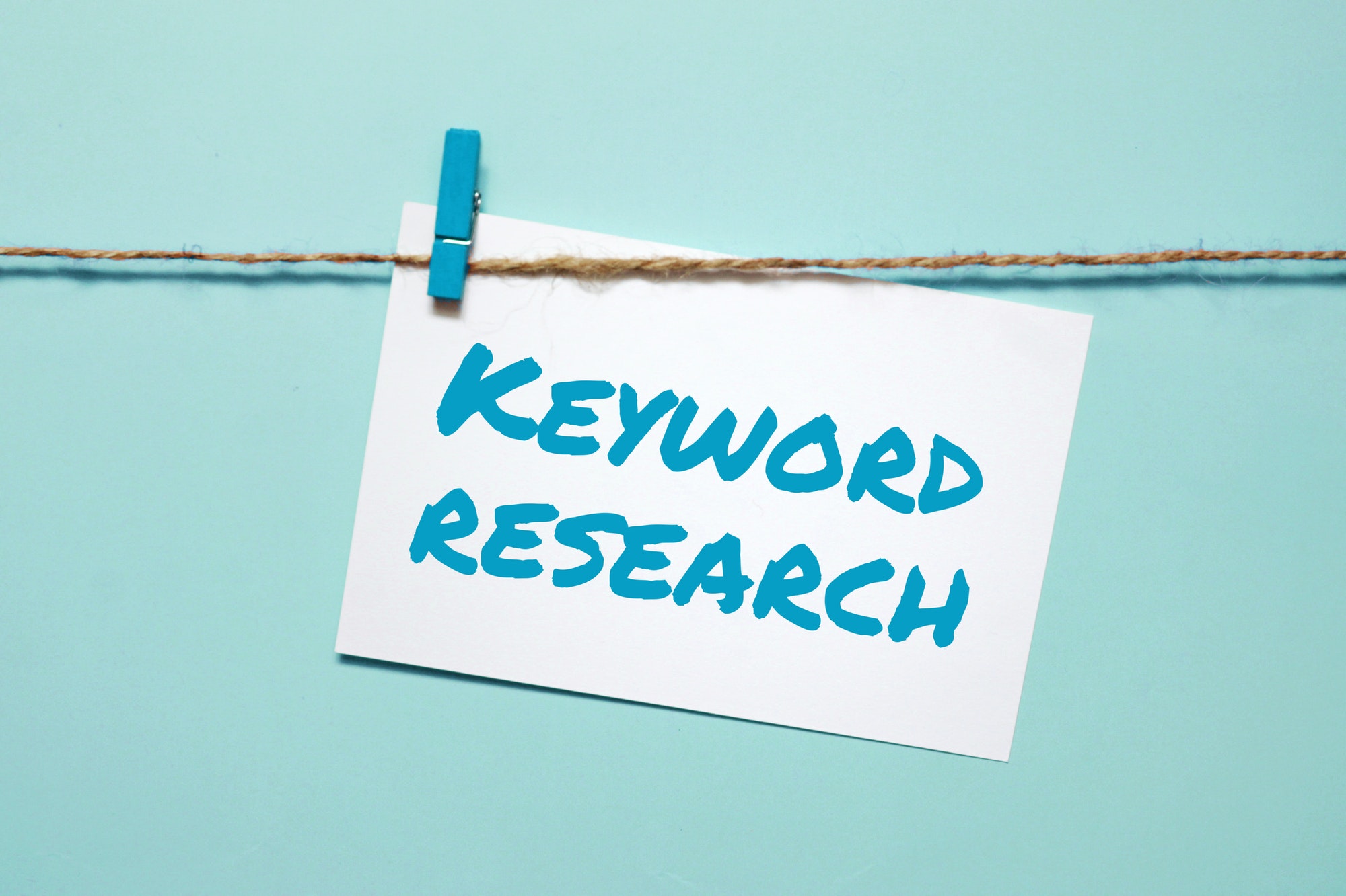 Sticker with the inscription keyword research hanging on a rope.