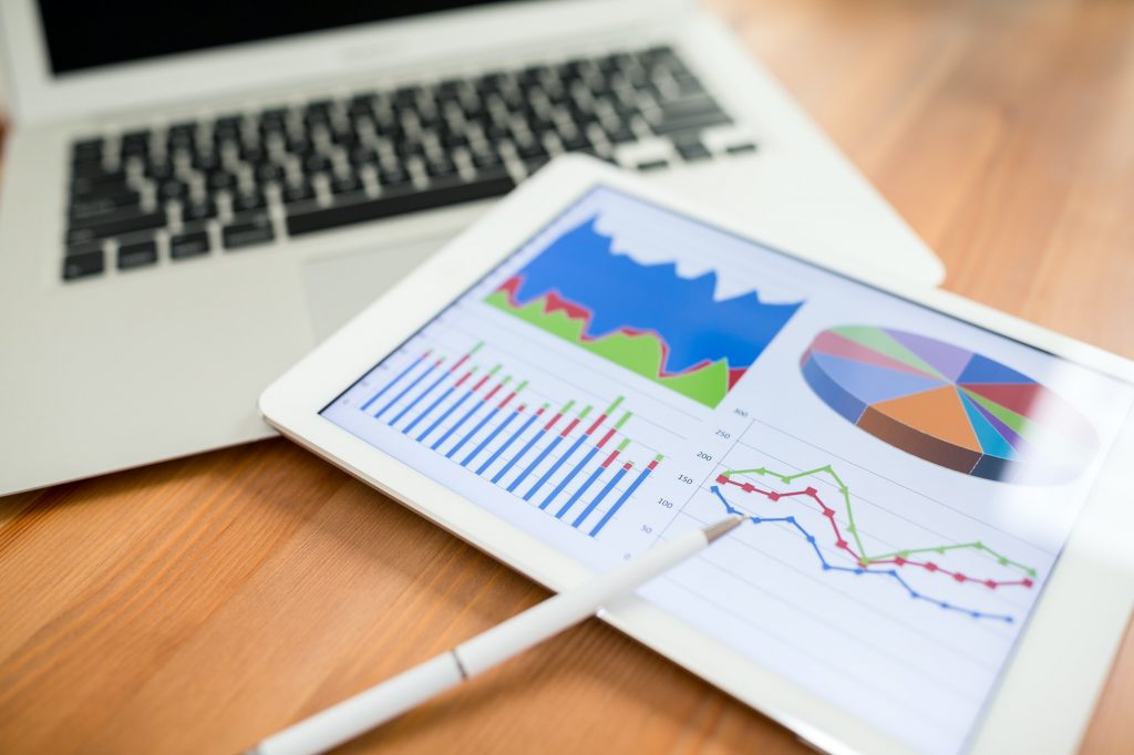 Why should you use data analytics for business? A laptop and tablet on a desk displaying data analytics.