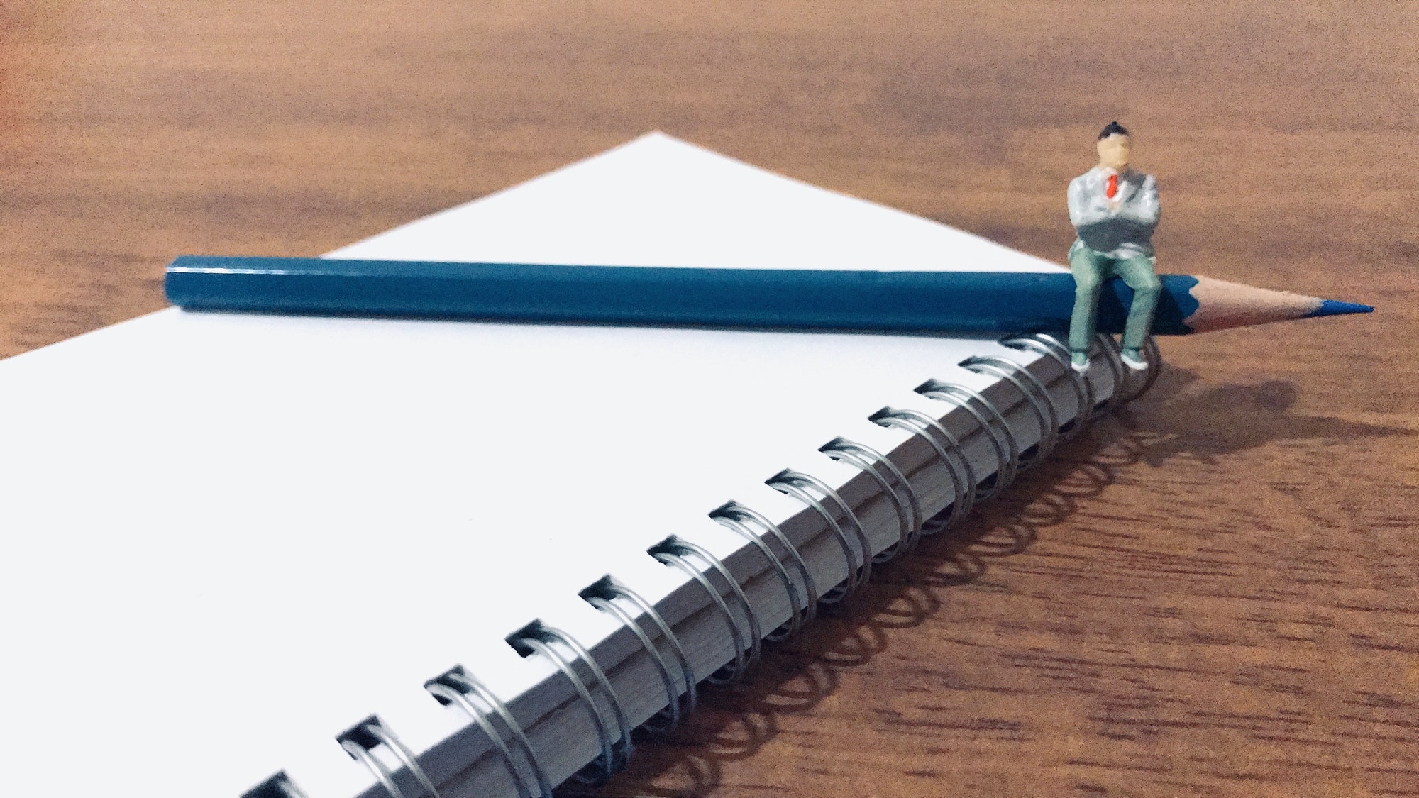 Tiny man sitting on a pencil and paper.