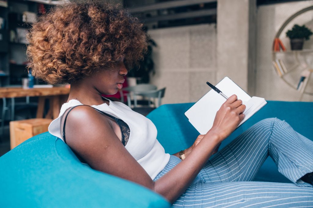 Young woman writing and working in modern coworking space.