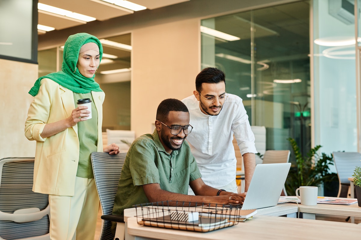 Employees Chatting And Looking At The Screen Of A Laptop