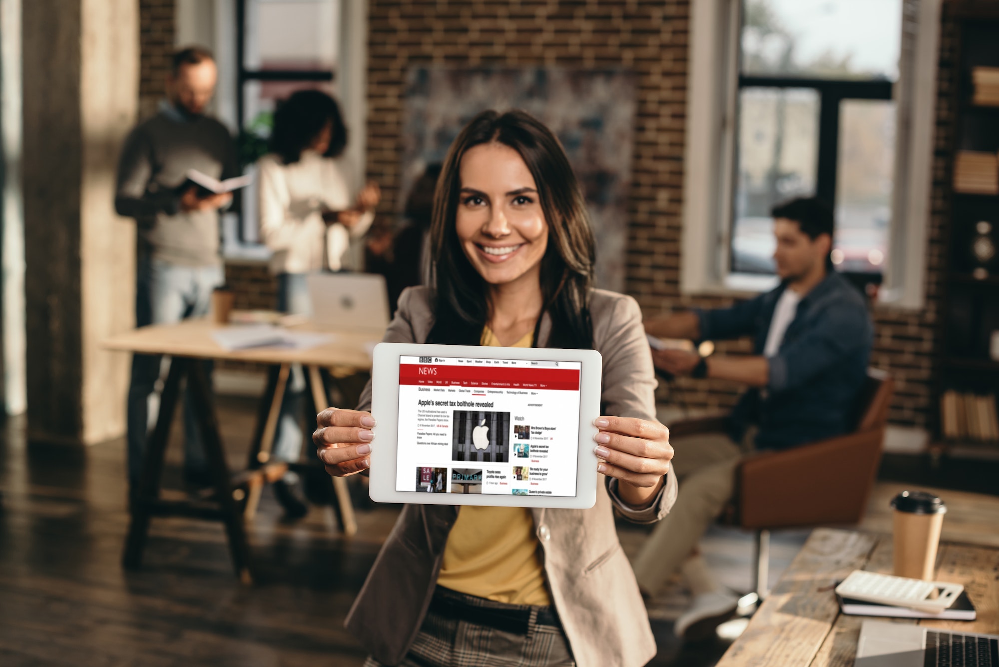 Happy businesswoman holding tablet explaining the 5 must-have features for your business website.