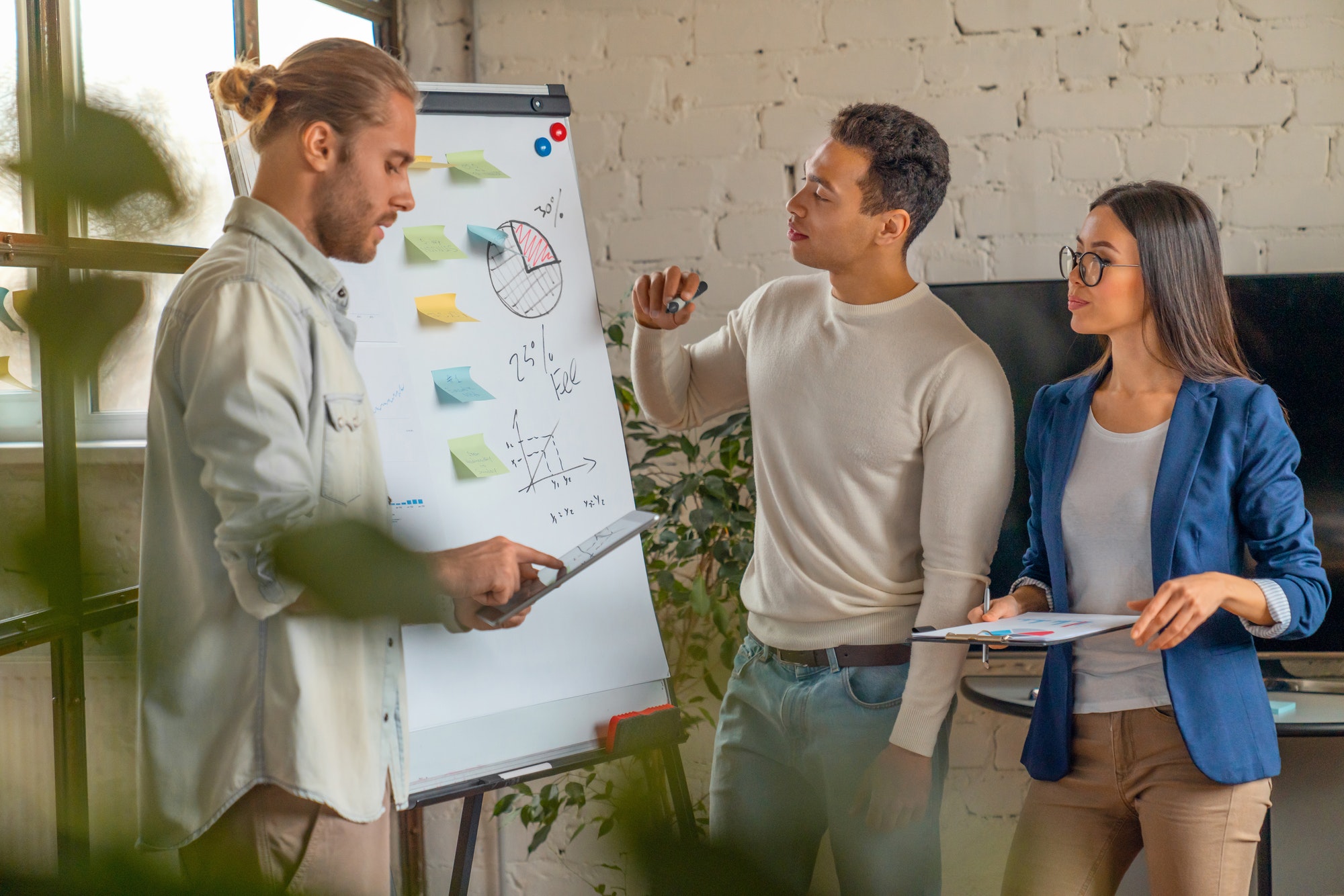 Young man standing by flip chart and giving presentation over new business startup.