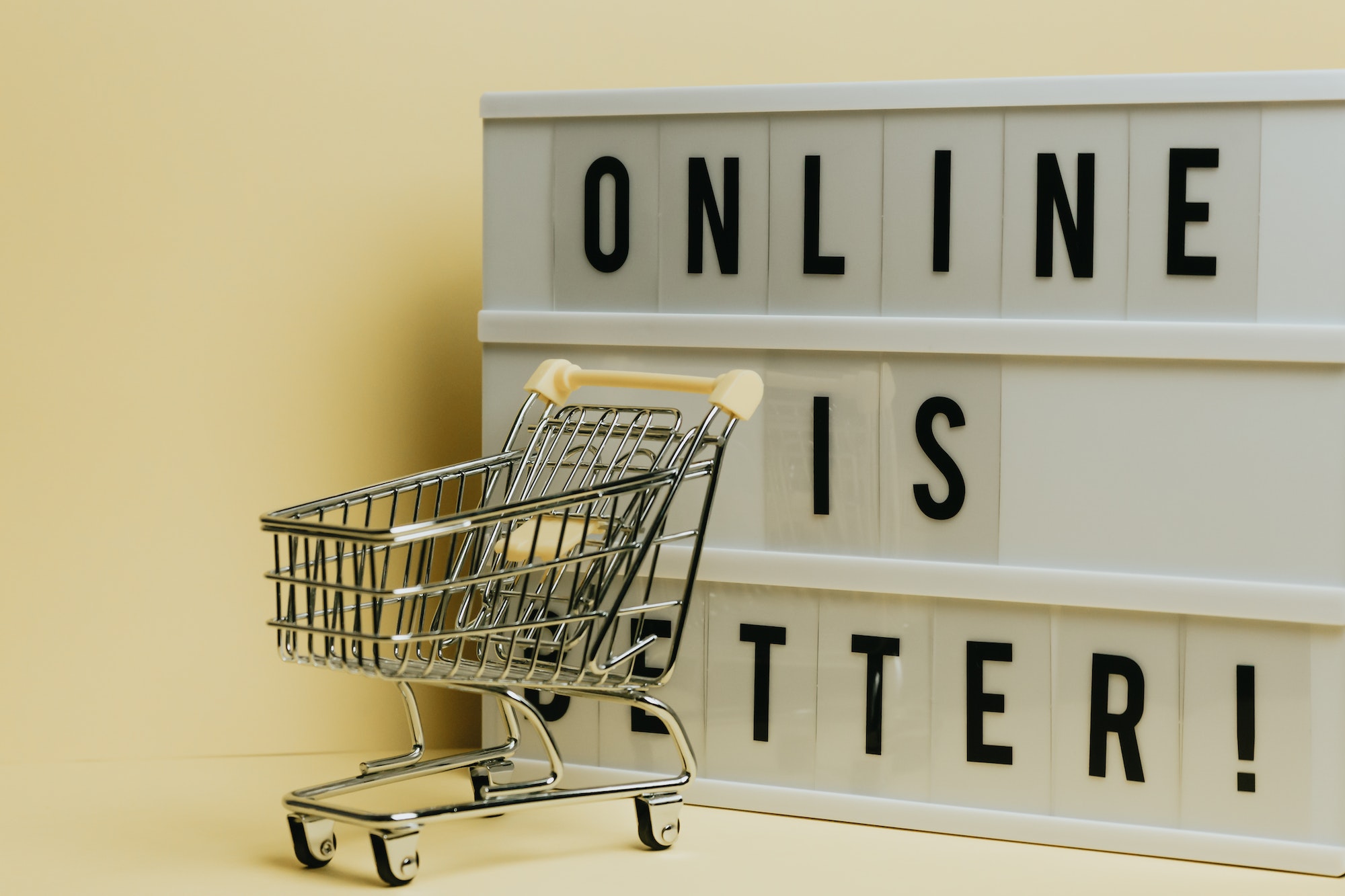 Ecommerce vs retail sign showing that online is better. Toy shopping cart in front of sign.