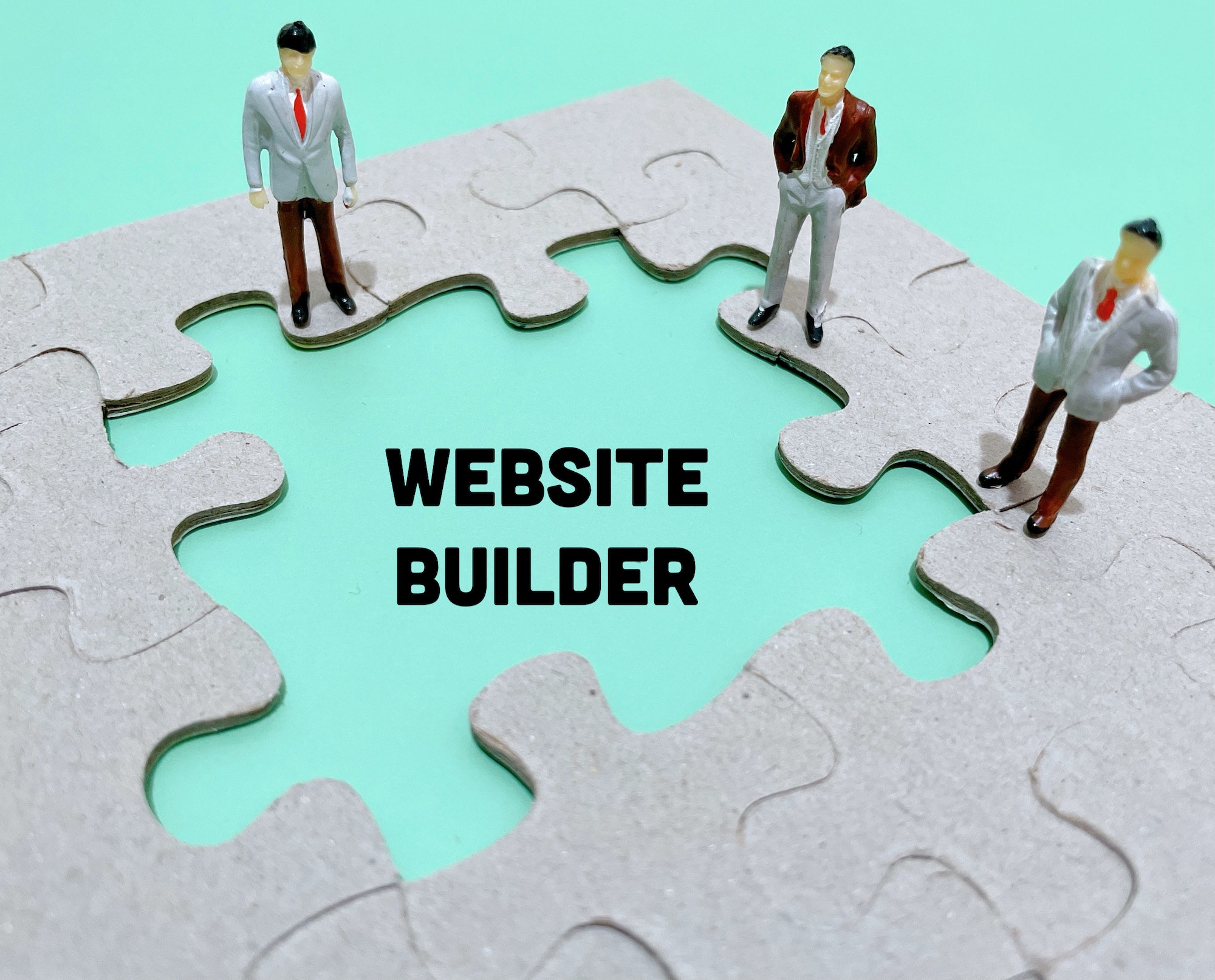 Website builder written inside puzzle pieces with toy people standing around it.