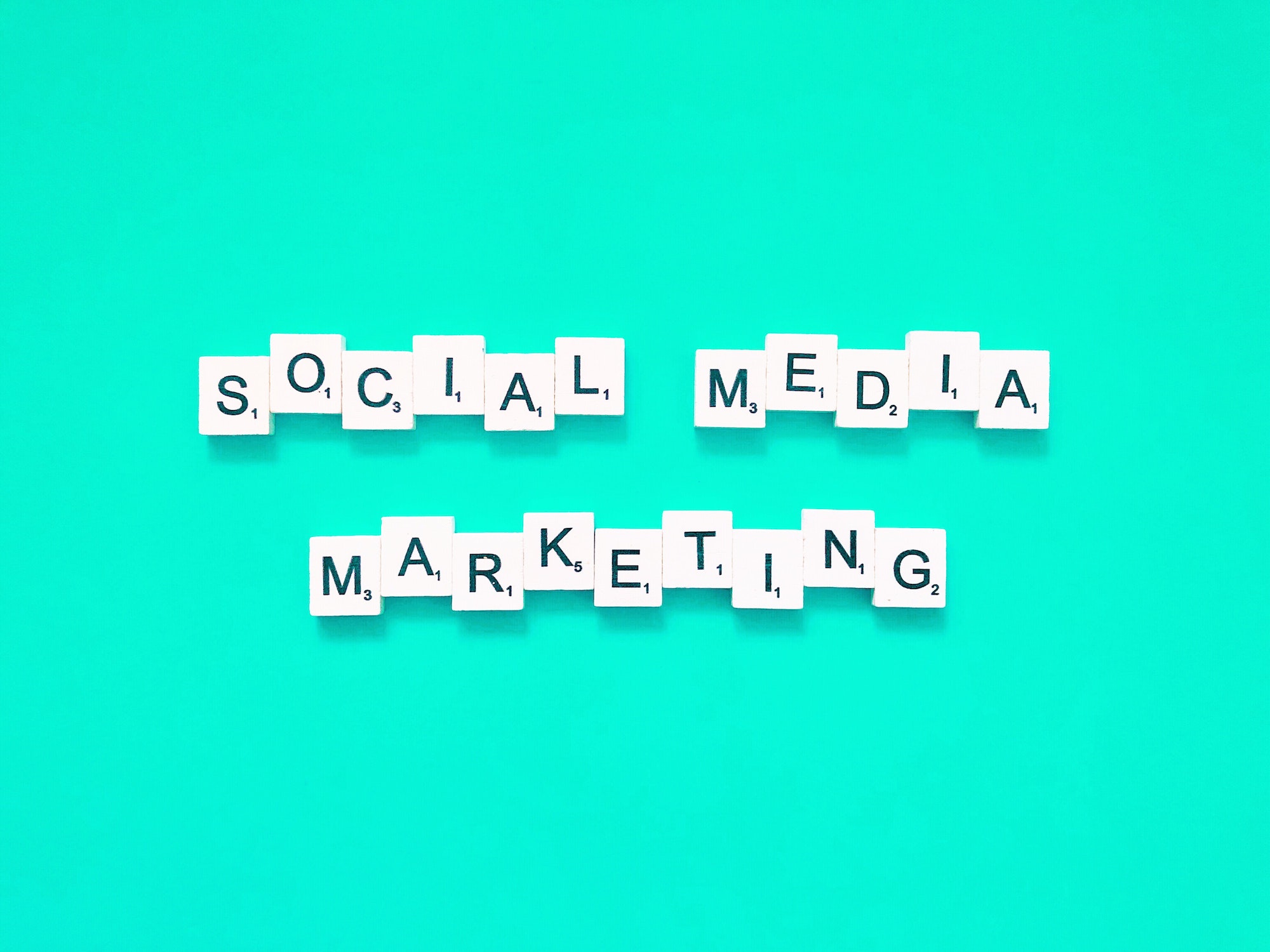 Social media marketing written on scrabble letters with a teal background.