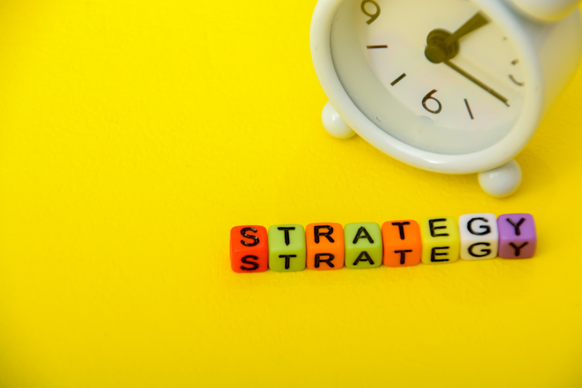 The word strategy written on blocks with a yellow background and a clock. Build A Market Penetration Strategy.
