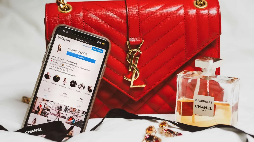 A phone with instagram open leaning on a purse.