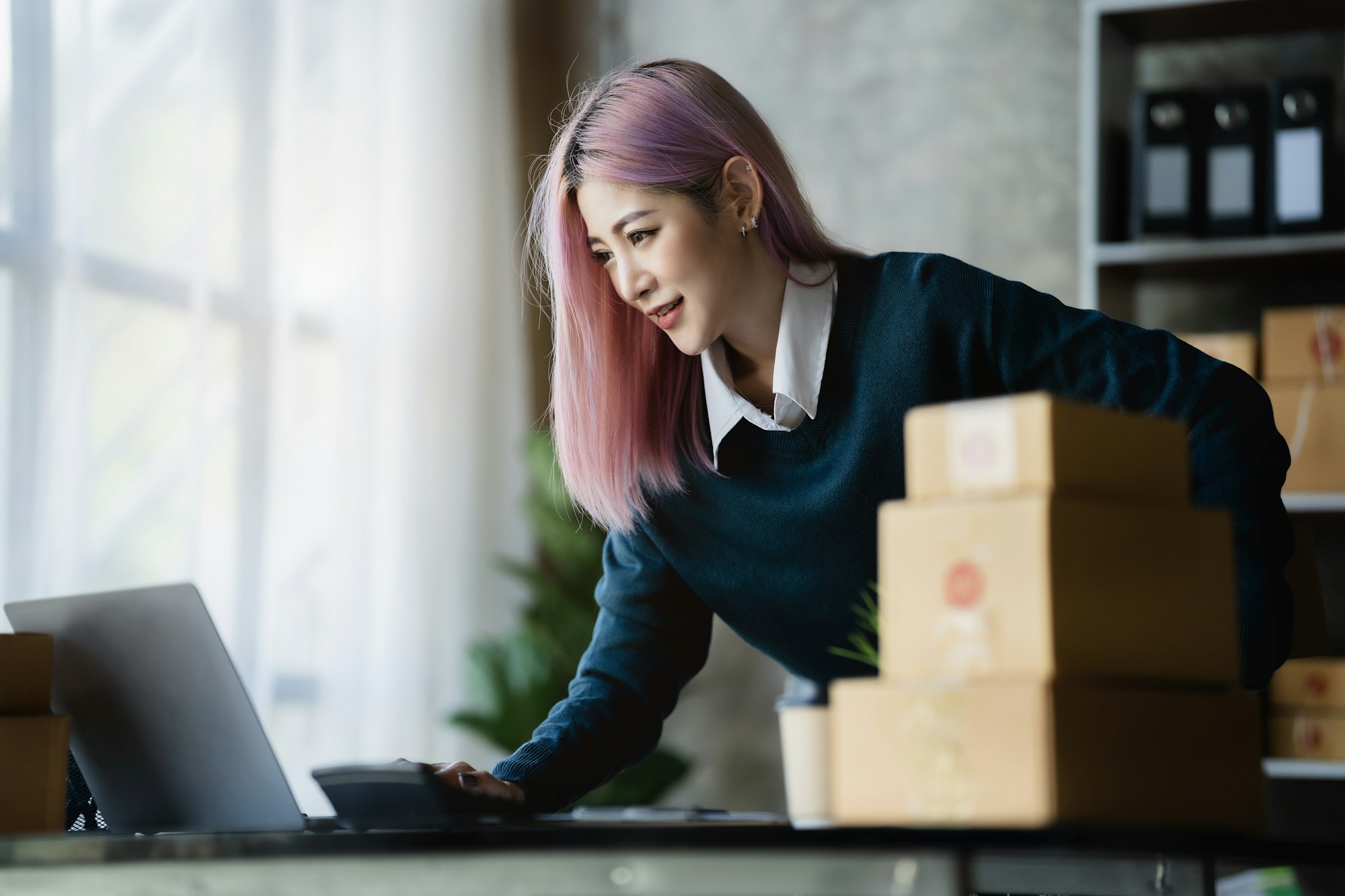Young women working in an office checking her eCommerce returns.