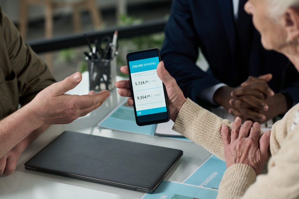 Senior woman learning to use banking app on her smartphone while having consultation with financial agent
